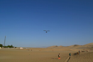 沙漠中人们在蓝天下滑沙