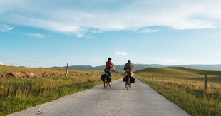 两人骑行于田园风光间