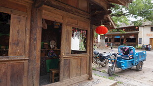 古朴木屋旁的蓝色三轮车