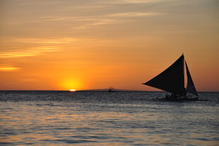 海上落日下的单桅帆船