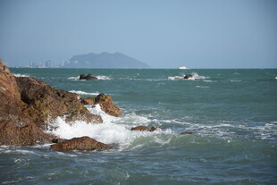 三亚海边礁石与海上船只景象