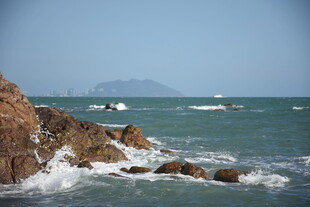 三亚海边礁石旁的海浪与船只