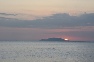 三亚海上日落时的孤舟远景