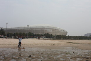 湛江沙滩上的人及远处体育场