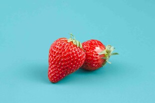 两颗鲜红草莓置于蓝背景