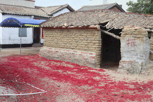 乡村旧屋前的红色鞭炮碎屑