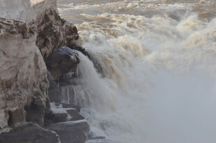汹涌河水冲击岸边石壁