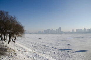 冬日河畔雪景与远处城市