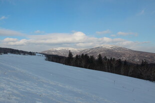 冬日雪坡与远处山林美景