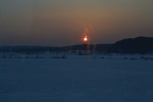夕阳下的雪地与远处灯塔