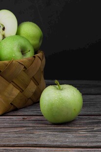 木桌上竹篮里的青苹果