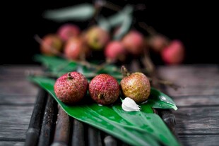 新鲜荔枝摆于绿叶竹席上