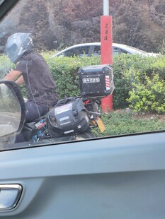 骑摩托的人从车旁经过