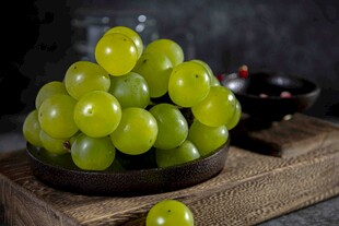 新鲜绿葡萄摆放在古朴木盘上