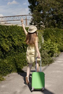 女子拖绿箱漫步户外