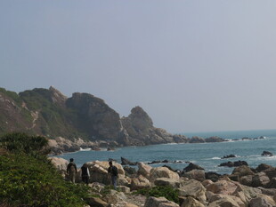 海岸边嶙峋岩石与青山海景