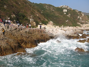 海边岩石处游人观浪景象