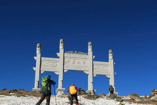 登山者前行于古朴牌坊下